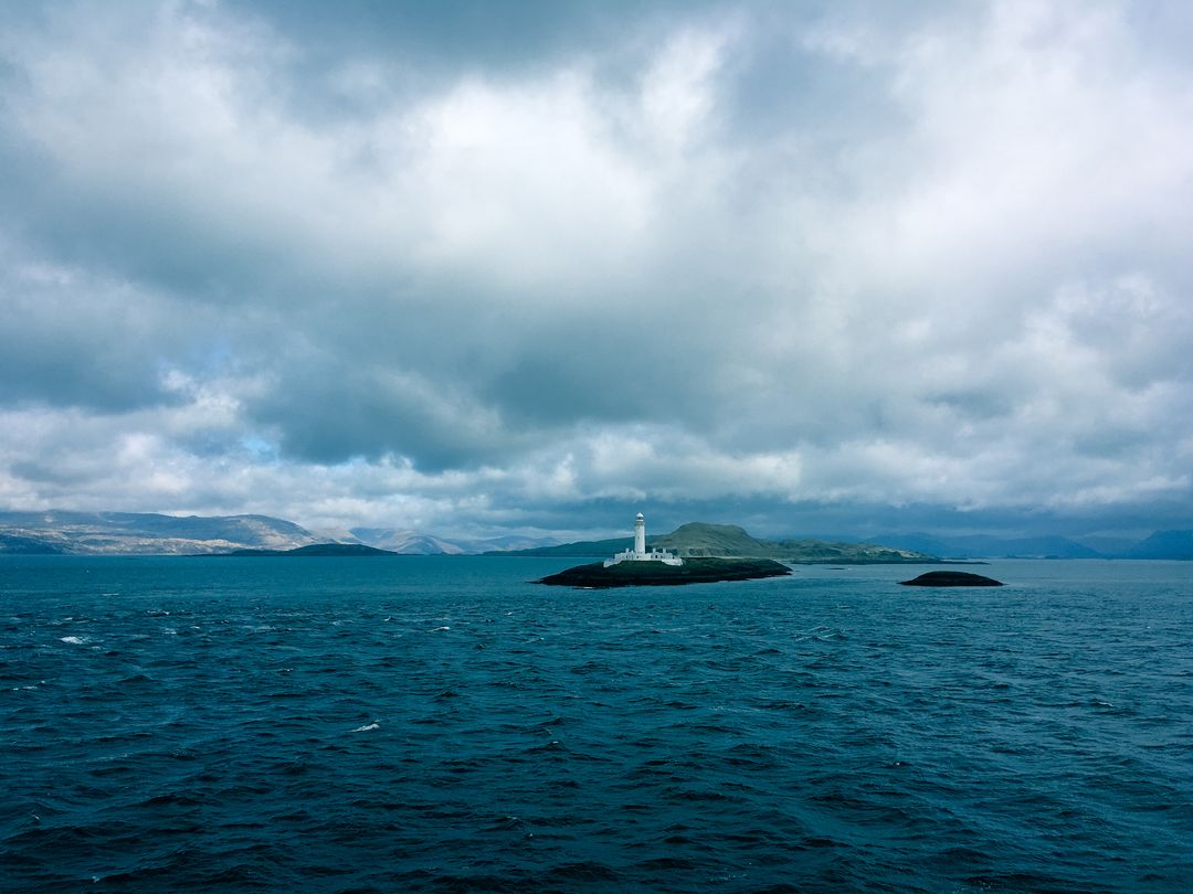 Solitary Lighthouse on Calm Waters Under Cloudy Sky - Free Images, Stock Photos and Pictures on Pikwizard.com