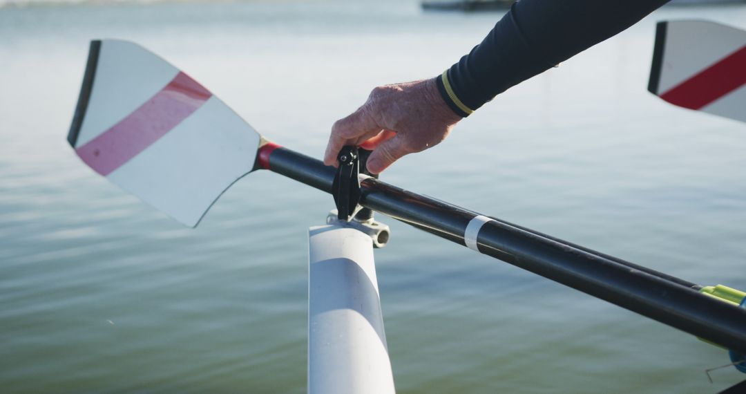 Hand gripping rowing oar on calm lake during practice - Free Images, Stock Photos and Pictures on Pikwizard.com