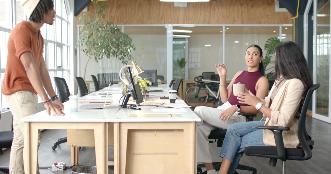 Diverse team collaborating around shared desk in modern open-plan office
