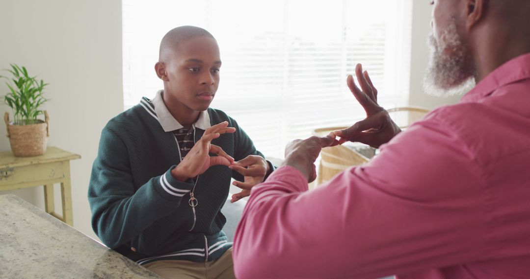 Young man learning sign language from elderly man at home - Free Images, Stock Photos and Pictures on Pikwizard.com