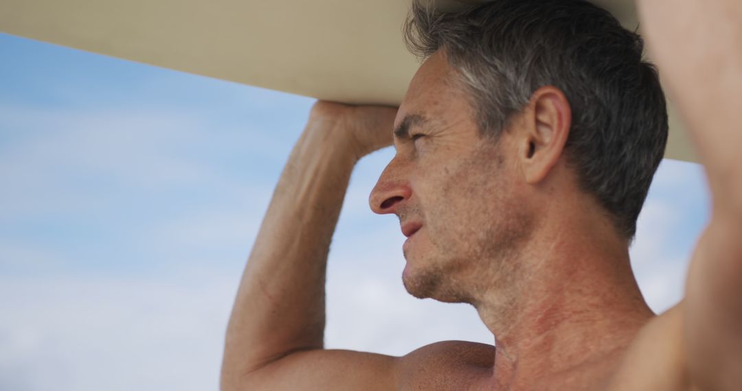 Mature man carrying surfboard on beach - Free Images, Stock Photos and Pictures on Pikwizard.com