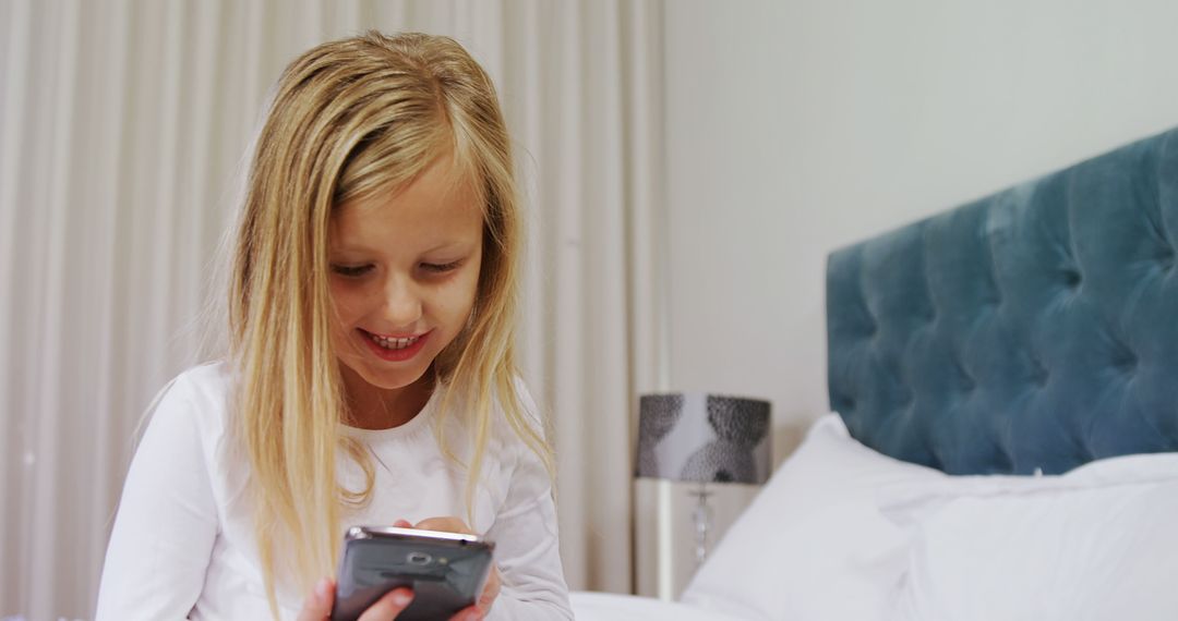 Young Girl Smiling While Playing on Smartphone in Bedroom - Free Images, Stock Photos and Pictures on Pikwizard.com