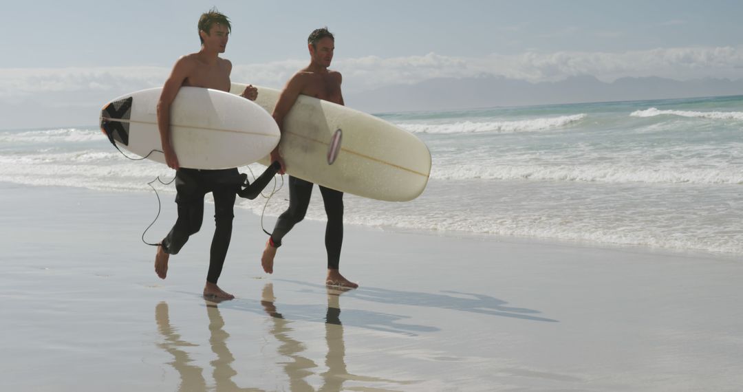 Surfers Running Along Beach with Surfboards - Free Images, Stock Photos and Pictures on Pikwizard.com