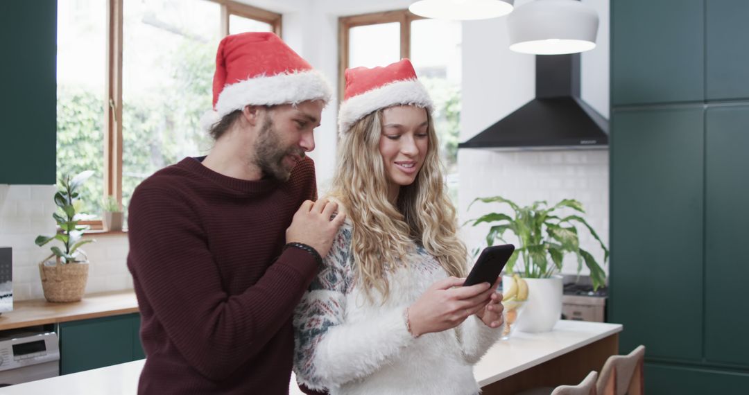 Happy Couple in Santa Hats Using Smartphone in Kitchen During Christmas - Free Images, Stock Photos and Pictures on Pikwizard.com