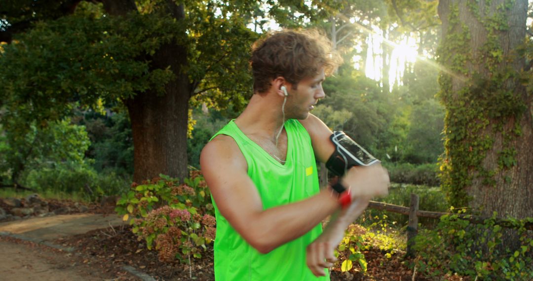 Man Checking Smartwatch While Jogging in Sunny Park - Free Images, Stock Photos and Pictures on Pikwizard.com