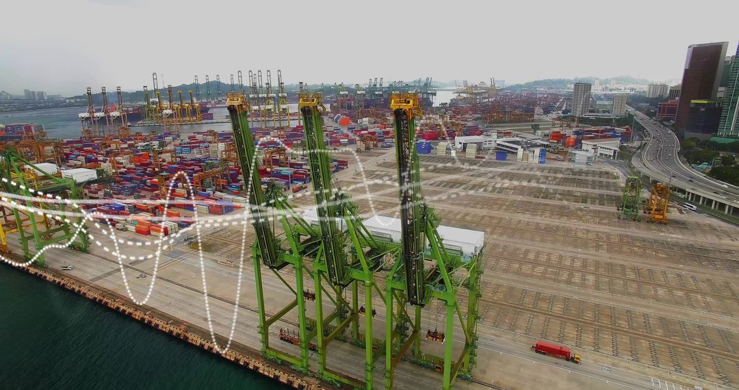 Green gantry cranes operating on quay stacking containers at busy coastal shipping terminal