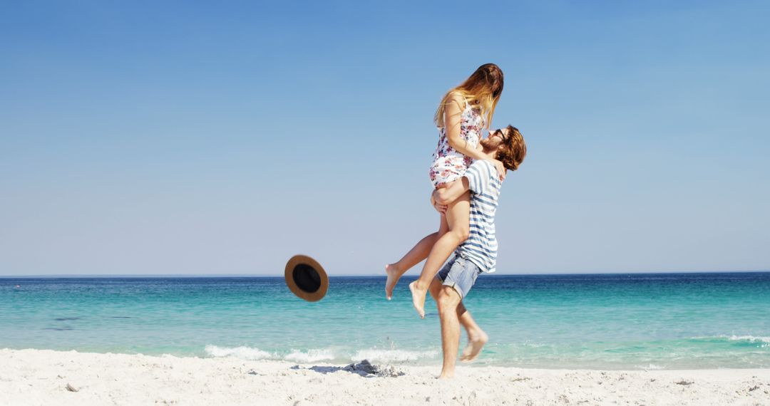 A joyful Caucasian couple shares a playful lift on a sunny beach, epitomizing summer romance. - Free Images, Stock Photos and Pictures on Pikwizard.com