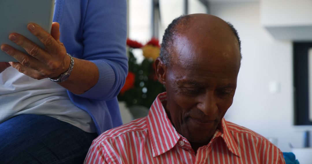 Senior African American Man Reflecting Indoors with Companion Holding Digital Tablet - Free Images, Stock Photos and Pictures on Pikwizard.com