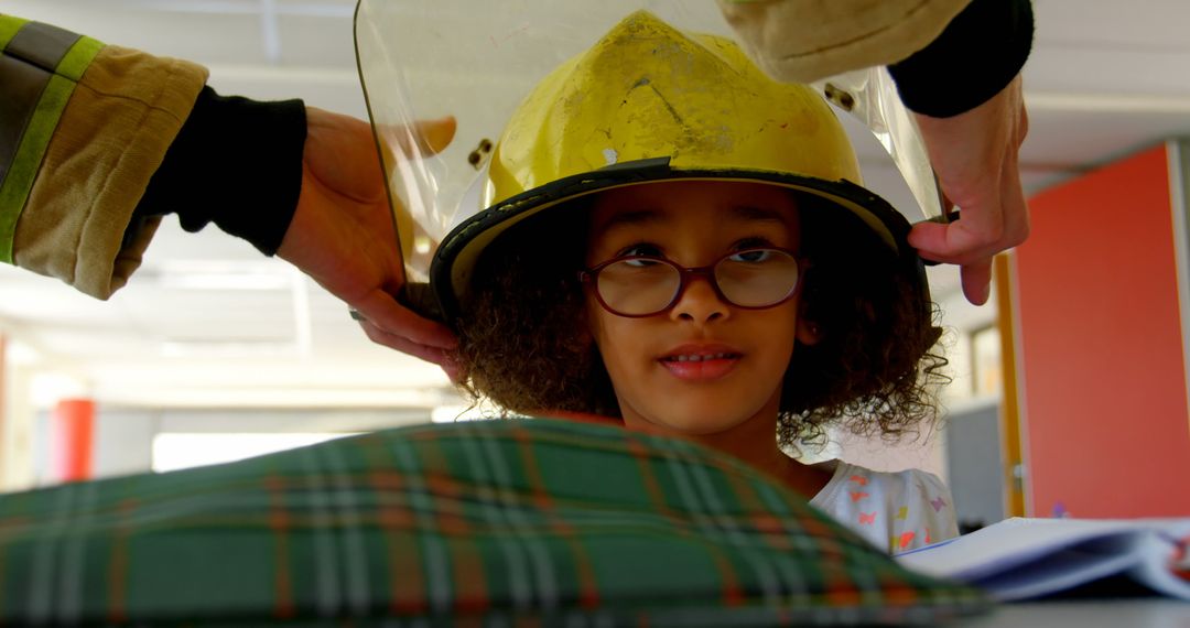 Firefighter Assisting Schoolgirl with Helmet in Classroom
