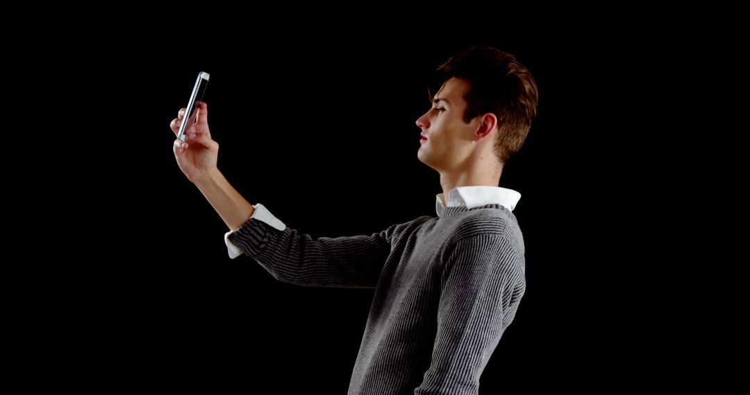 Young Man Taking Selfie During Casual Moment Against Dark Background - Free Images, Stock Photos and Pictures on Pikwizard.com