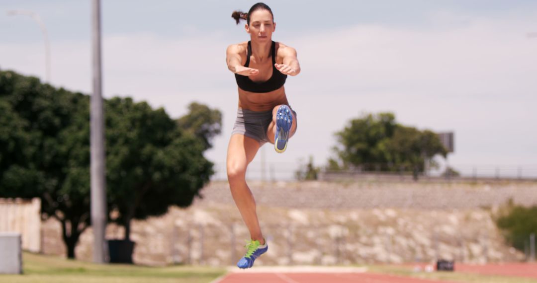 Female Athlete Mid-Jump on Outdoor Track - Free Images, Stock Photos and Pictures on Pikwizard.com