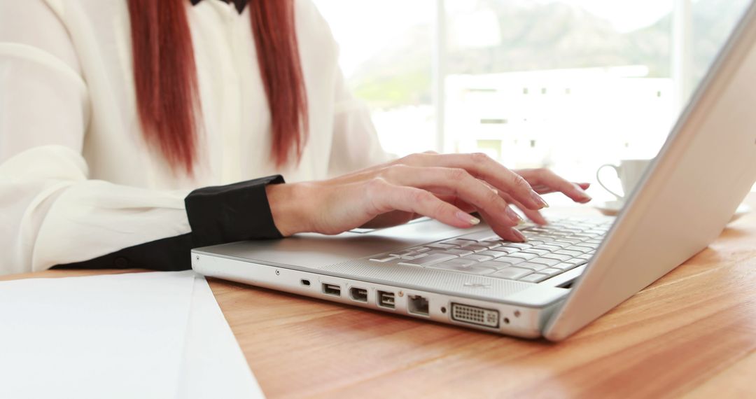 Focused Professional Woman Typing on Laptop in Bright Workspace