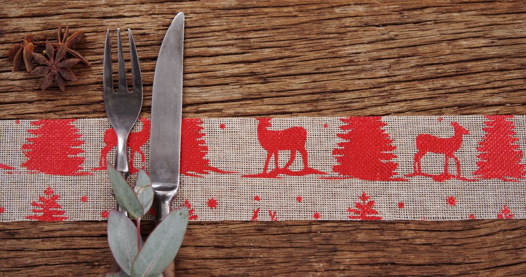 A cozy, rustic Christmas table setting is adorned with festive cutlery, greenery, and star anise. - Free Images, Stock Photos and Pictures on Pikwizard.com