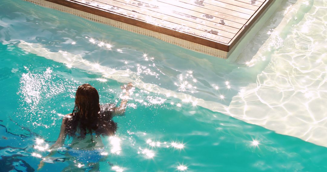 Woman Enjoying a Leisurely Swim in Sparkling Pool - Free Images, Stock Photos and Pictures on Pikwizard.com