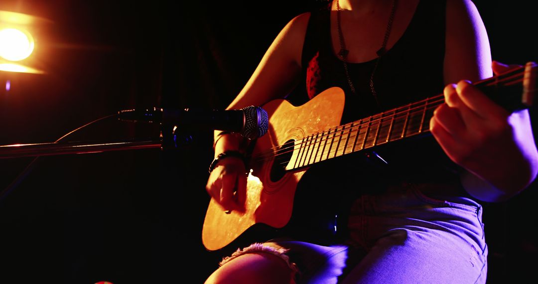 Female Musician Playing Acoustic Guitar on Stage with Microphone - Free Images, Stock Photos and Pictures on Pikwizard.com