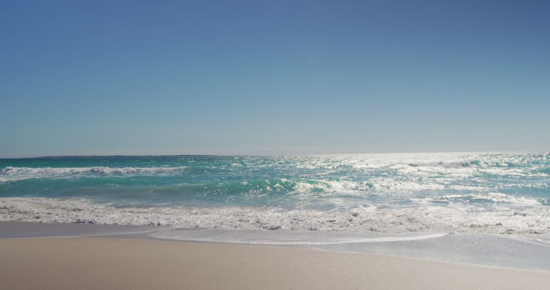 Serene Sandy Beach with Blue Ocean Waves Under Clear Sky - Free Images, Stock Photos and Pictures on Pikwizard.com