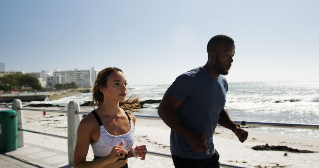 Fit couple jogging along sunny beach promenade