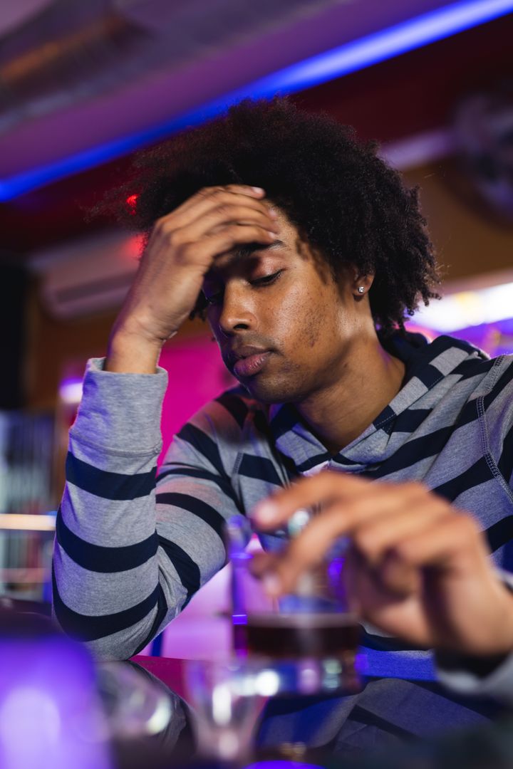 Vertical image of sad african american man sitting in pub - Free Images, Stock Photos and Pictures on Pikwizard.com