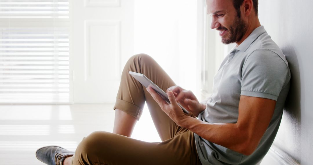 Man Sitting on Floor Using Digital Tablet in Bright Modern Home - Free Images, Stock Photos and Pictures on Pikwizard.com