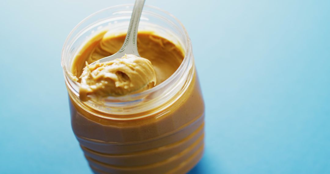Creamy Peanut Butter in Jar on Bright Blue Background