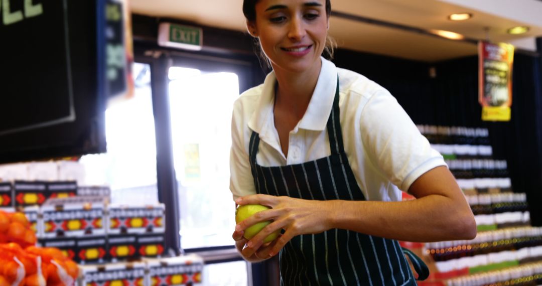 Grocery Store Clerk Holding Fruit and Smiling - Free Images, Stock Photos and Pictures on Pikwizard.com