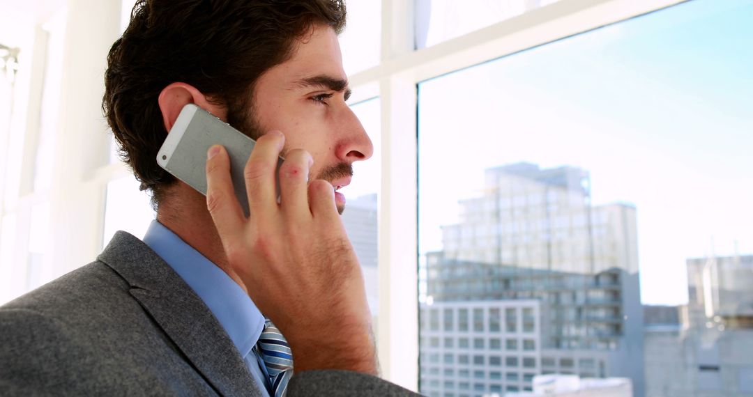 Businessman Making Phone Call in Modern Office with City View - Free Images, Stock Photos and Pictures on Pikwizard.com