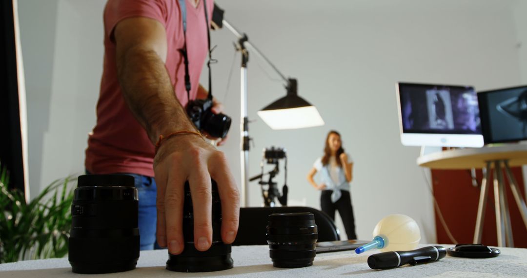 Photographer setting up equipment in studio with model in background - Free Images, Stock Photos and Pictures on Pikwizard.com