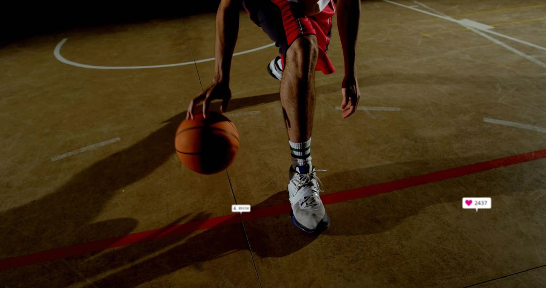 Basketball player dribbling low on indoor court, driving move, dynamic shadow