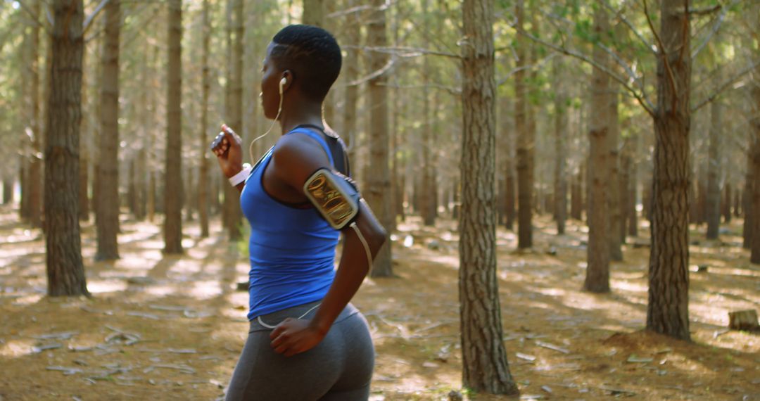 Woman Jogging in Forest Wearing Sportswear and Listening to Music - Free Images, Stock Photos and Pictures on Pikwizard.com