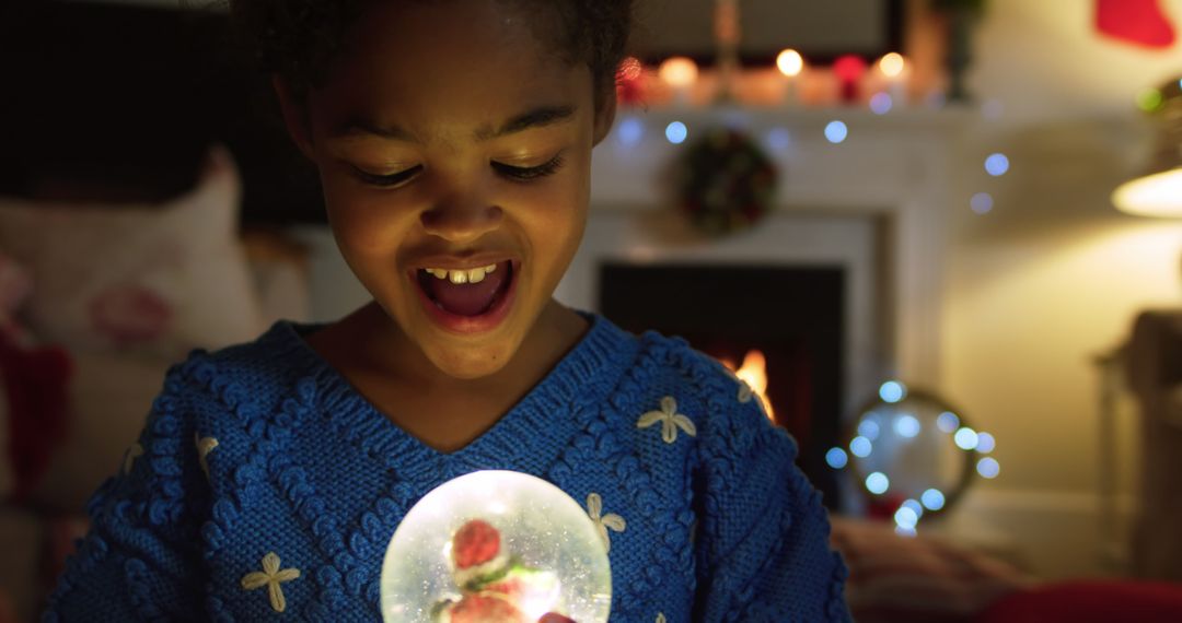 Excited Child Holding Glowing Snow Globe During Christmas - Free Images, Stock Photos and Pictures on Pikwizard.com