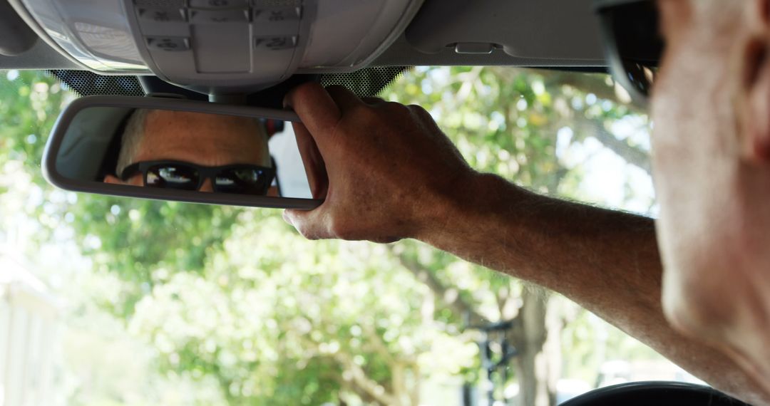 Man Adjusting Rearview Mirror in Car on Sunny Day - Free Images, Stock Photos and Pictures on Pikwizard.com