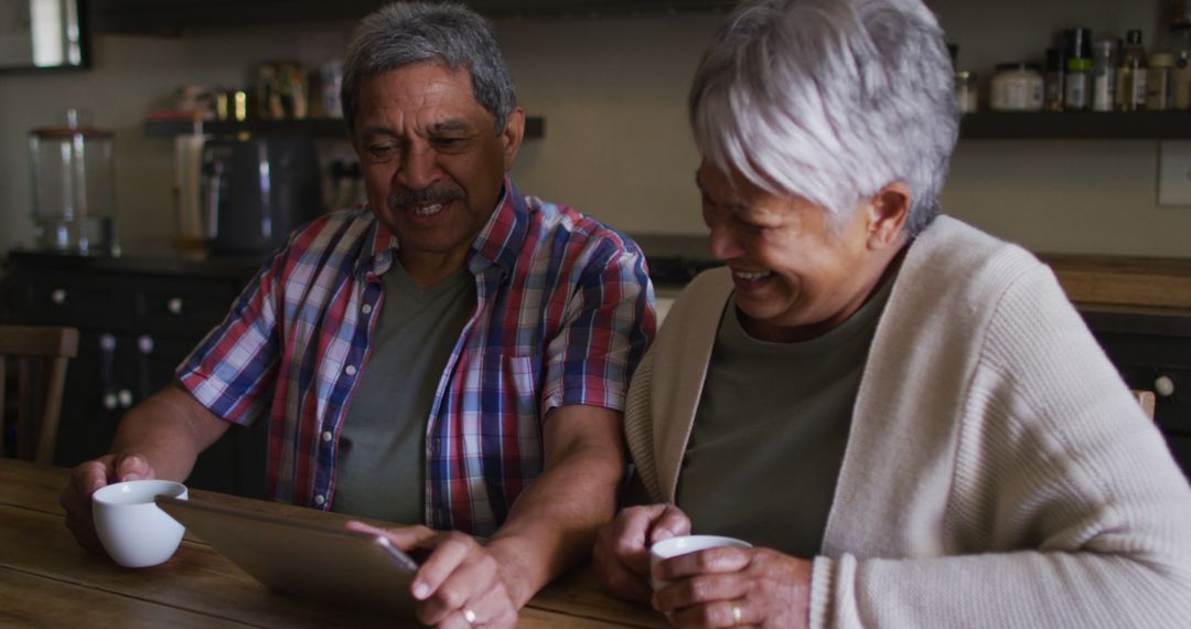 Joyful Senior Couple Using Tablet at Home for Relaxation