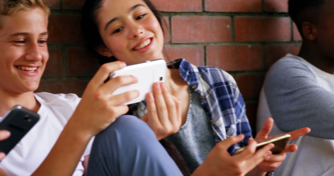 Teenagers Smiling and Using Smartphones Together - Free Images, Stock Photos and Pictures on Pikwizard.com