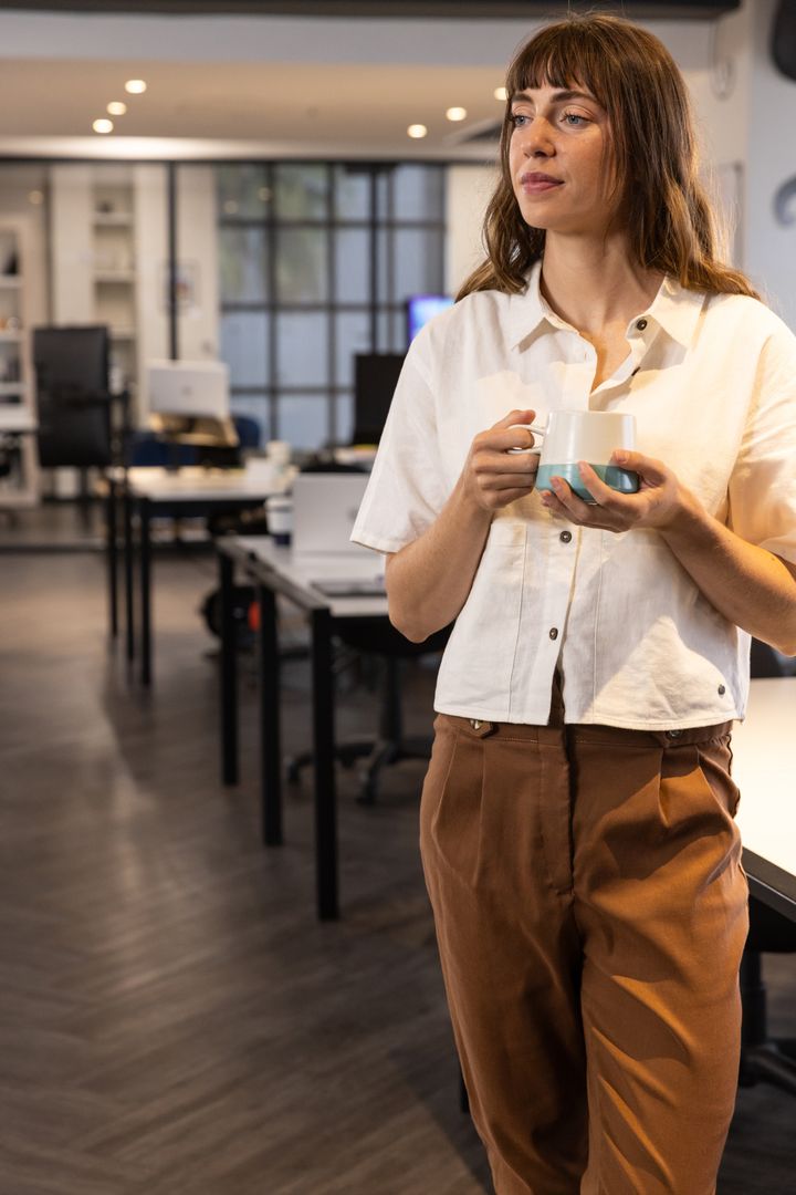 Confident Professional Holding Mug in Modern Office Environment