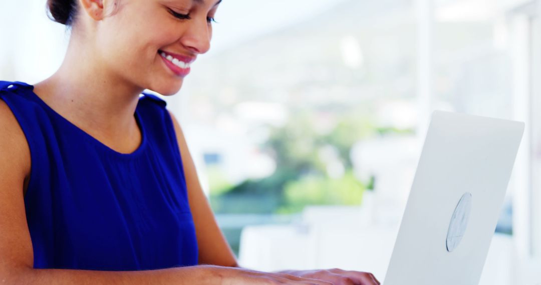 Businesswoman Smiling While Typing on Laptop