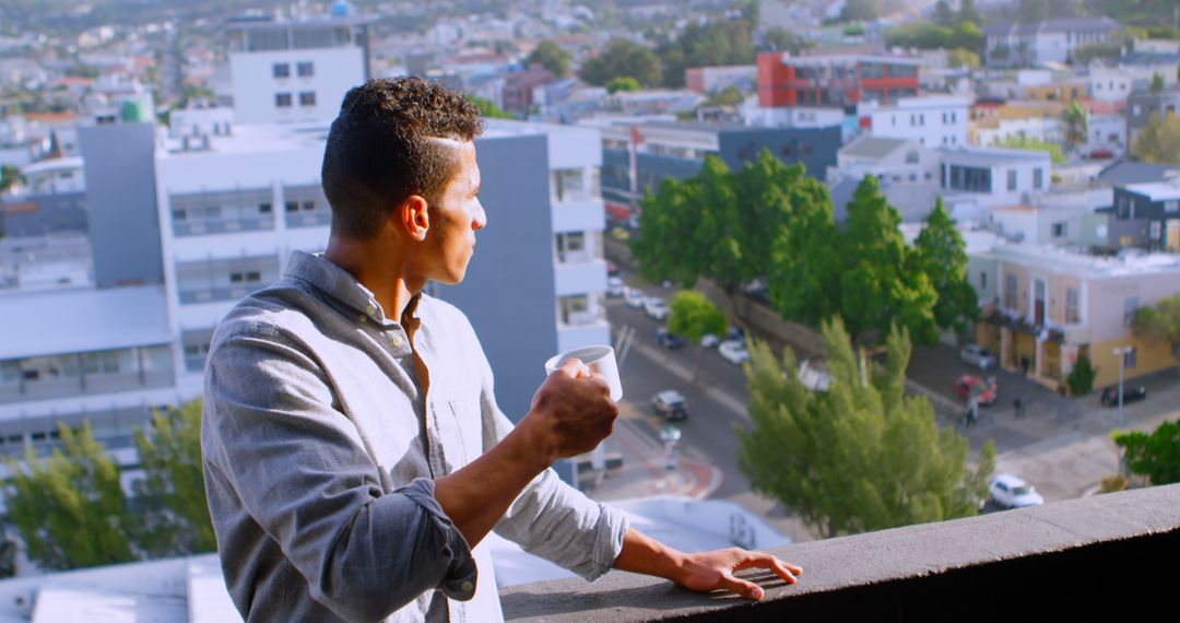 Man Enjoys Coffee on Balcony Overlooking Urban Landscape - Free Images, Stock Photos and Pictures on Pikwizard.com