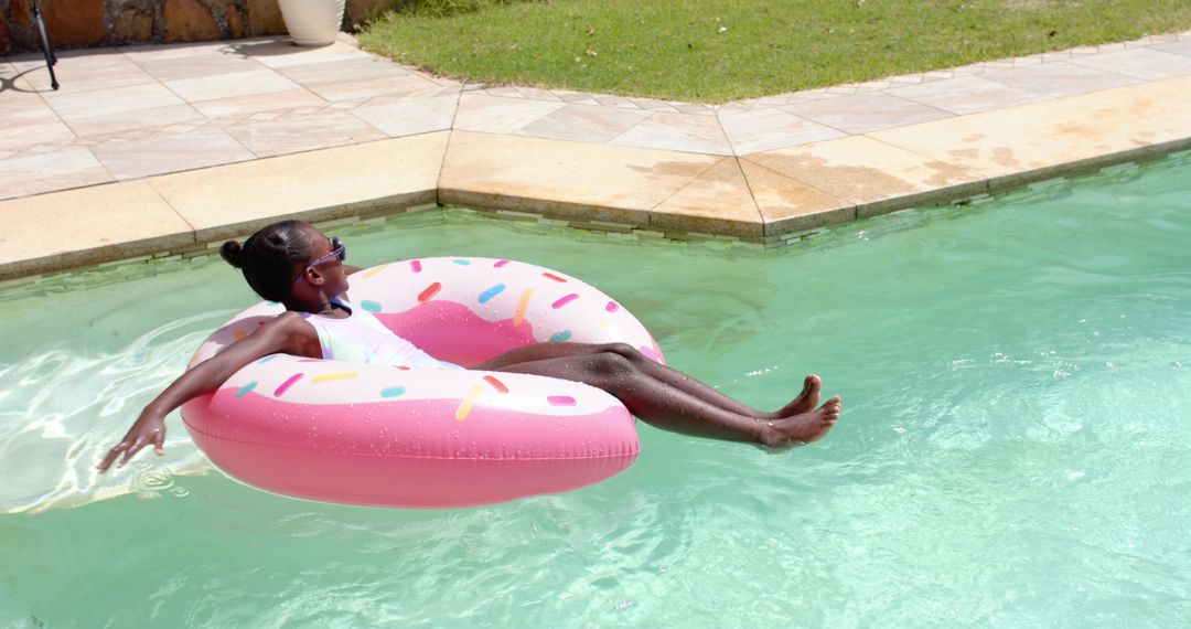 Youth Relaxing on Colorful Donut Float in Sunny Poolside