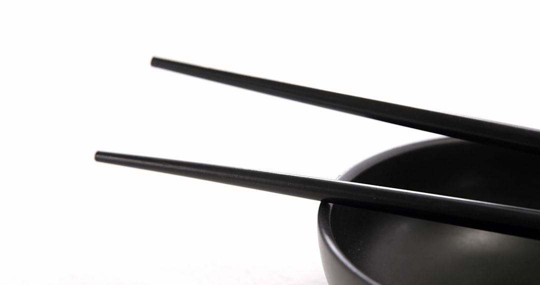 A pair of black chopsticks rests on a matching bowl, with copy space - Free Images, Stock Photos and Pictures on Pikwizard.com