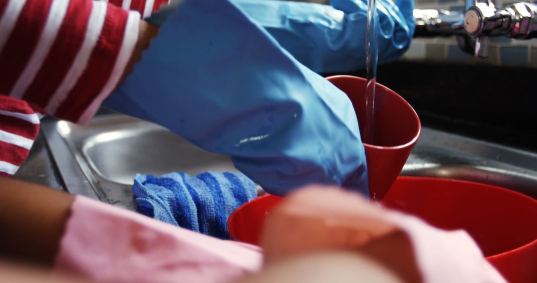 Person Washing Red Utensils in Kitchen Sink with Rubber Gloves - Free Images, Stock Photos and Pictures on Pikwizard.com