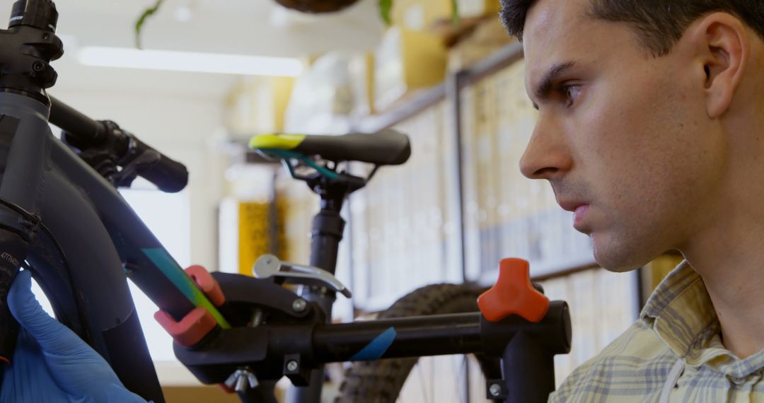 Man Repairing Bicycle in Workshop with Focused Look - Free Images, Stock Photos and Pictures on Pikwizard.com