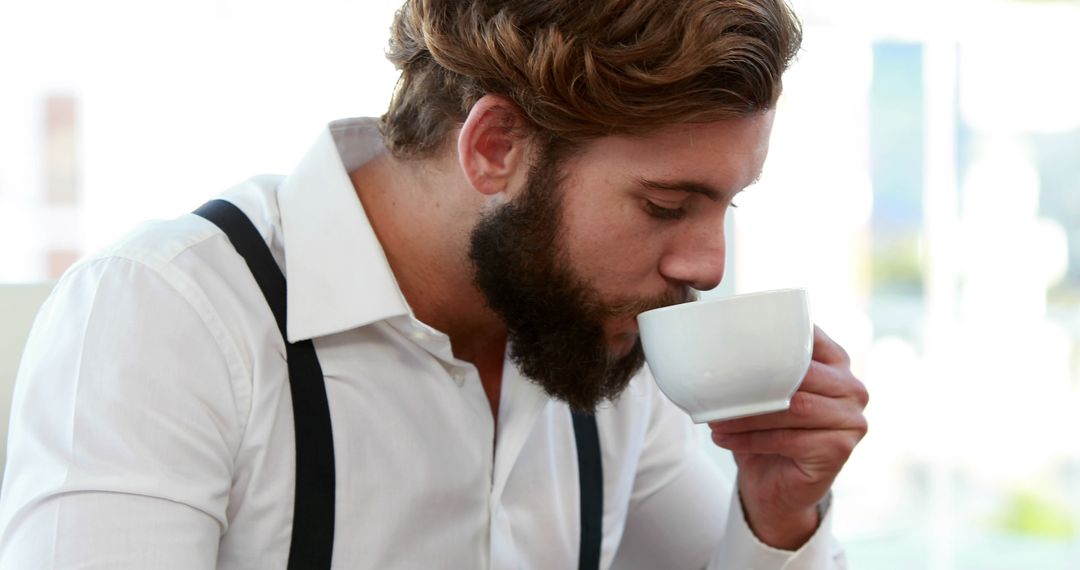 Bearded Man Sipping Coffee in Bright Office - Free Images, Stock Photos and Pictures on Pikwizard.com