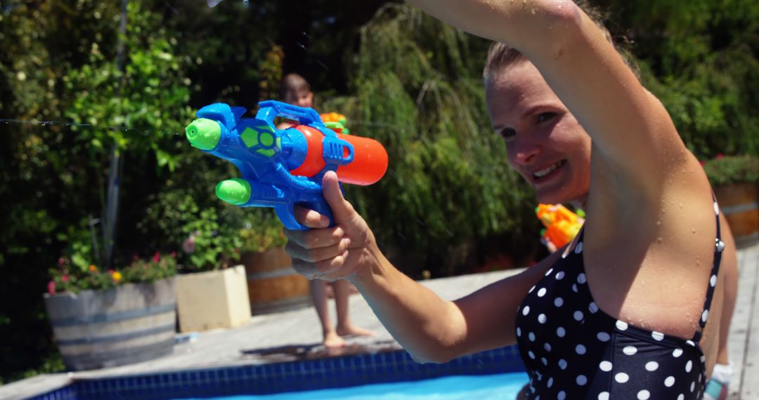 Woman Joyfully Using Water Gun Poolside on Sunny Day - Free Images, Stock Photos and Pictures on Pikwizard.com