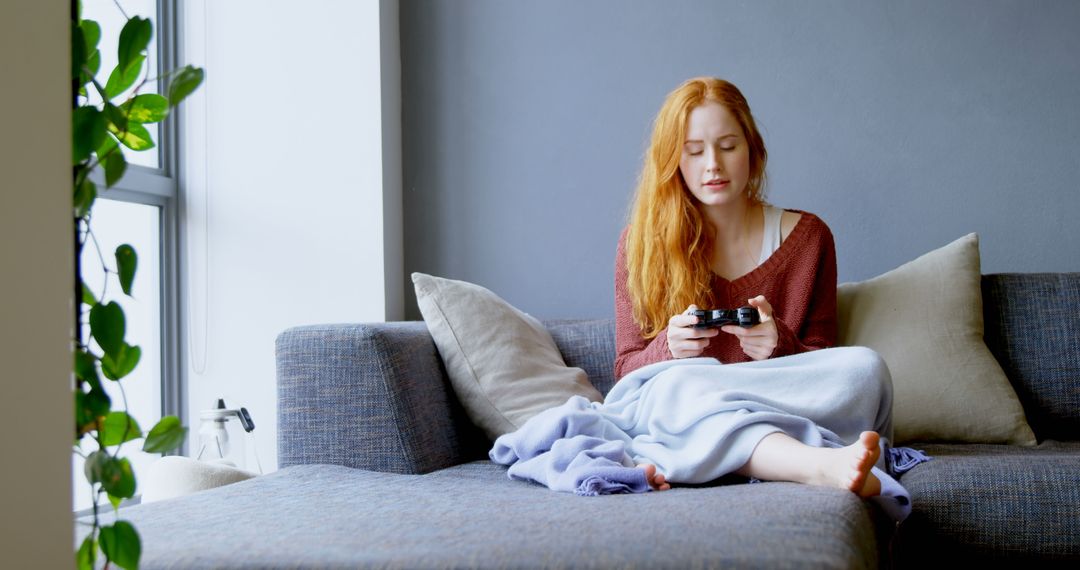 Young Woman Relaxing on Sofa at Home Playing Video Games - Free Images, Stock Photos and Pictures on Pikwizard.com