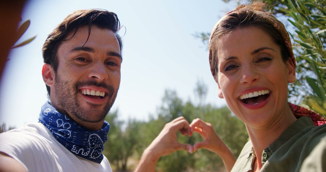 Happy Couple Creating Heart Gesture in Sunny Outdoors