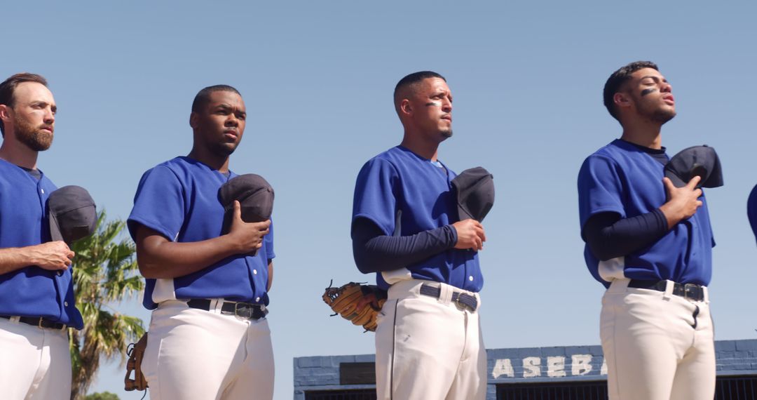 Baseball players standing with hats over hearts before game - Free Images, Stock Photos and Pictures on Pikwizard.com