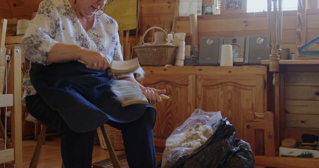 Senior Woman Carding Wool in Rustic Workshop - Free Images, Stock Photos and Pictures on Pikwizard.com