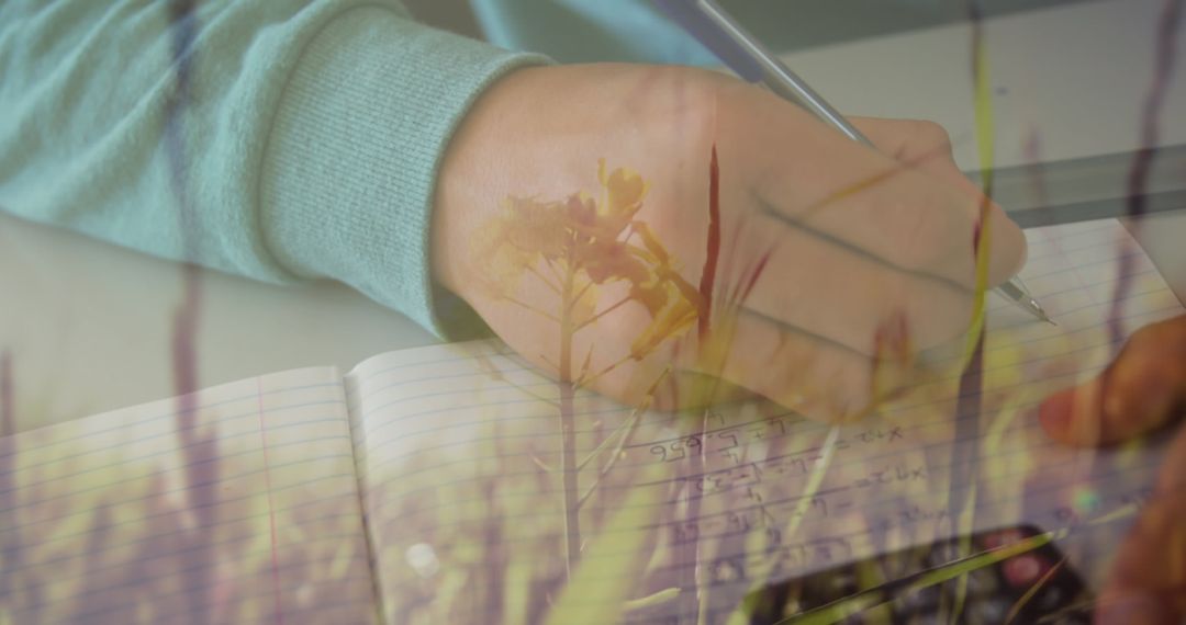 Close-Up of Hand Writing Notebook with Creative Floral Overlay