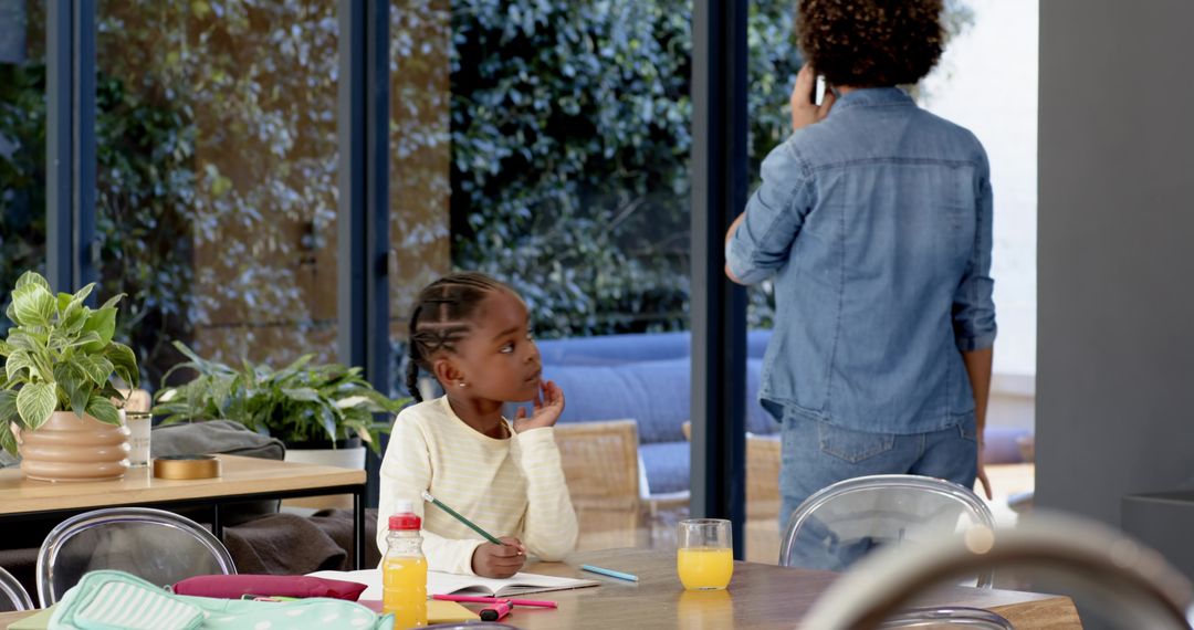 Child Doing Homework While Mother Talks on Smartphone Nearby