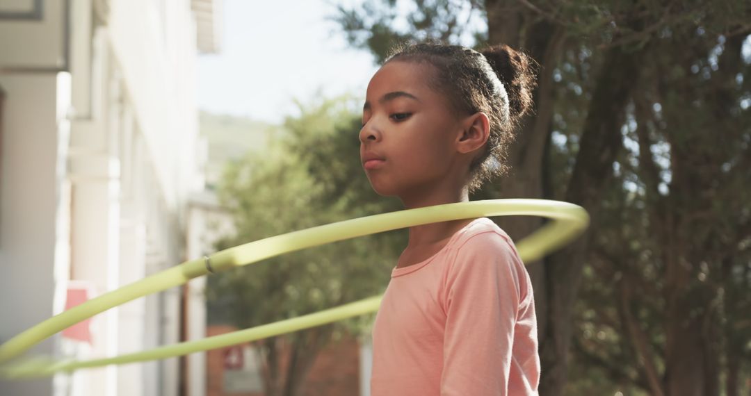 Child Playing with Hula Hoop Outdoors in Sunny Environment