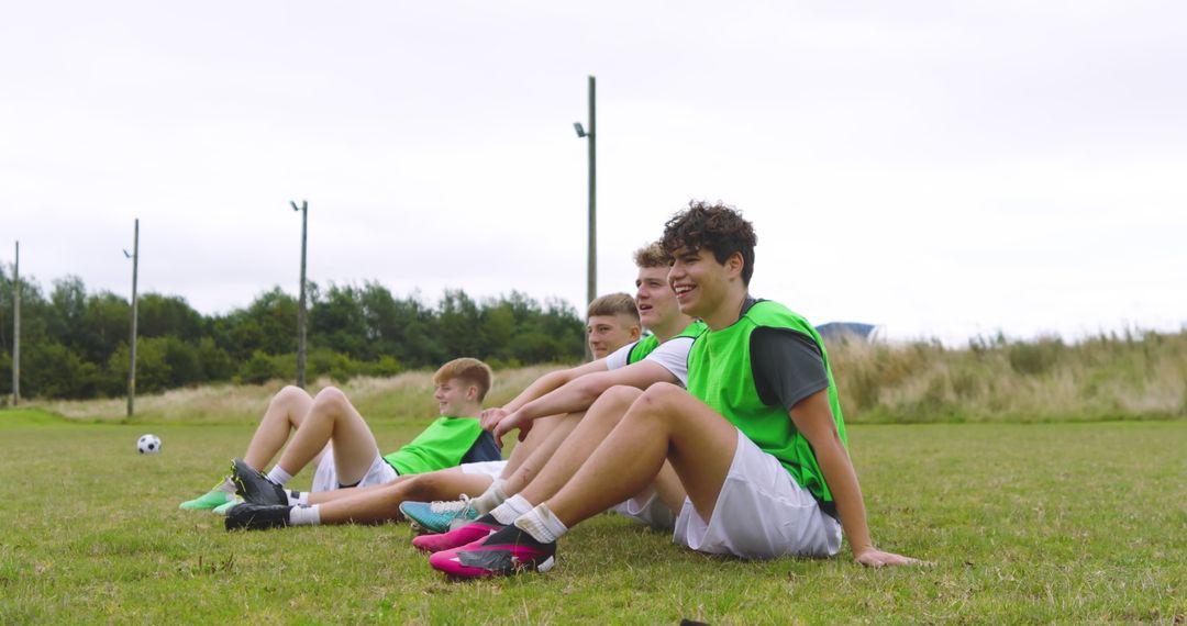 Teen Soccer Team Relaxing on Field in Green Training Jerseys